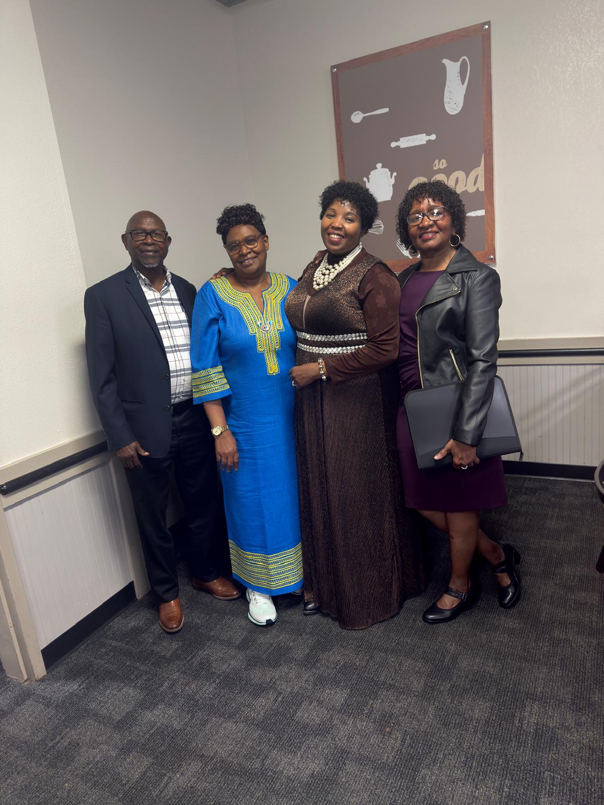 Four community members in formal attire posing together